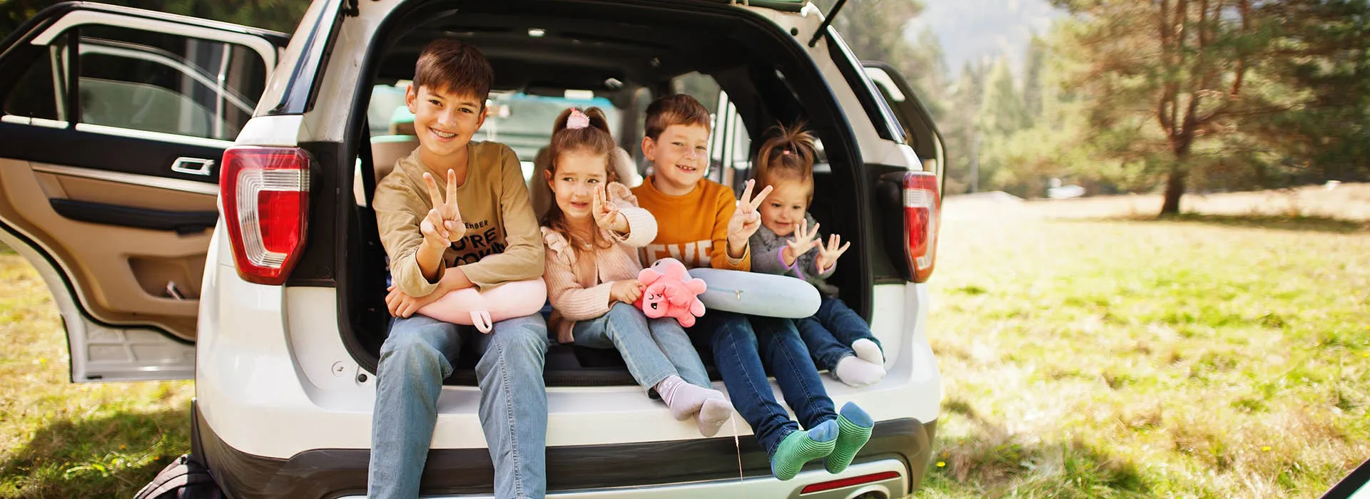 four smiling children in car boot